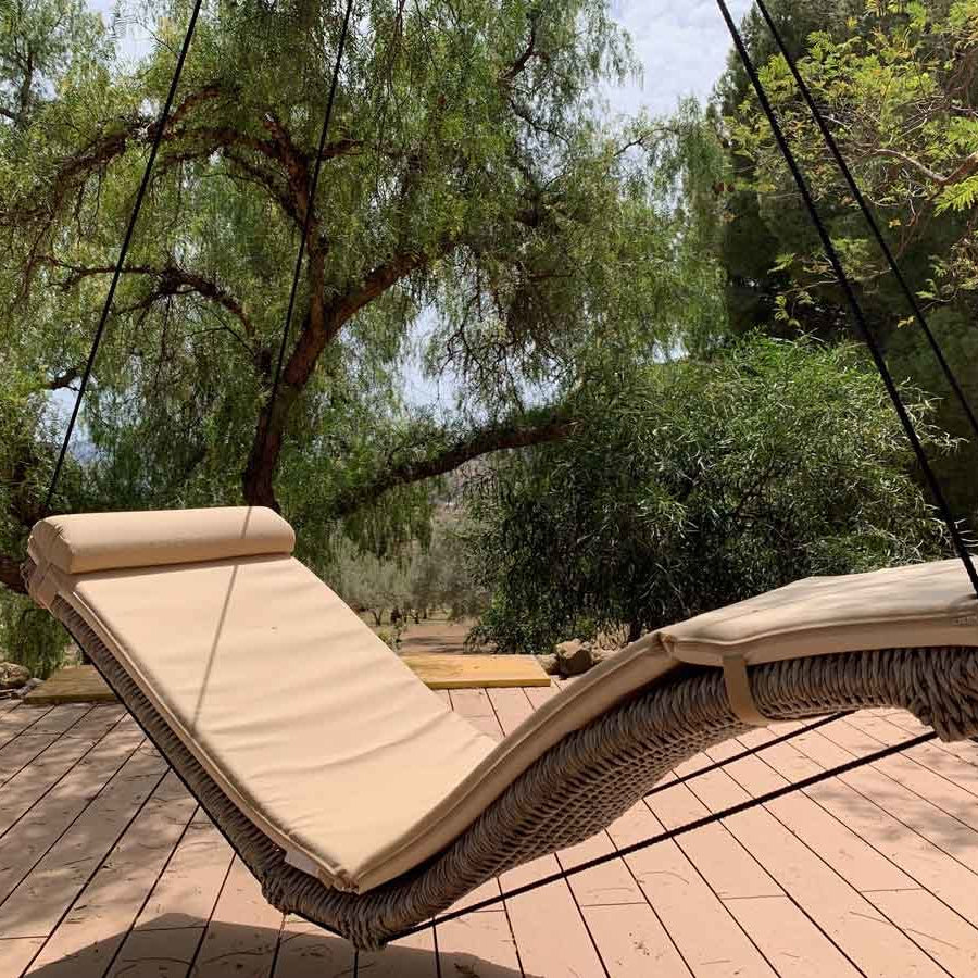 Two lounge chairs on a wooden deck with trees in the background